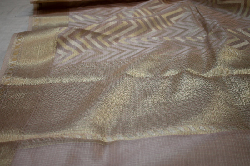 Shades of Benares presents a stunning baby pink Banarasi Tissue Silk Saree with gold & silver stripes.
