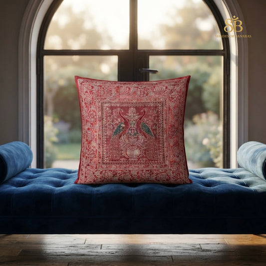 Red brocade Banarasi cushion cover with paired bird motif on a blue velvet daybed