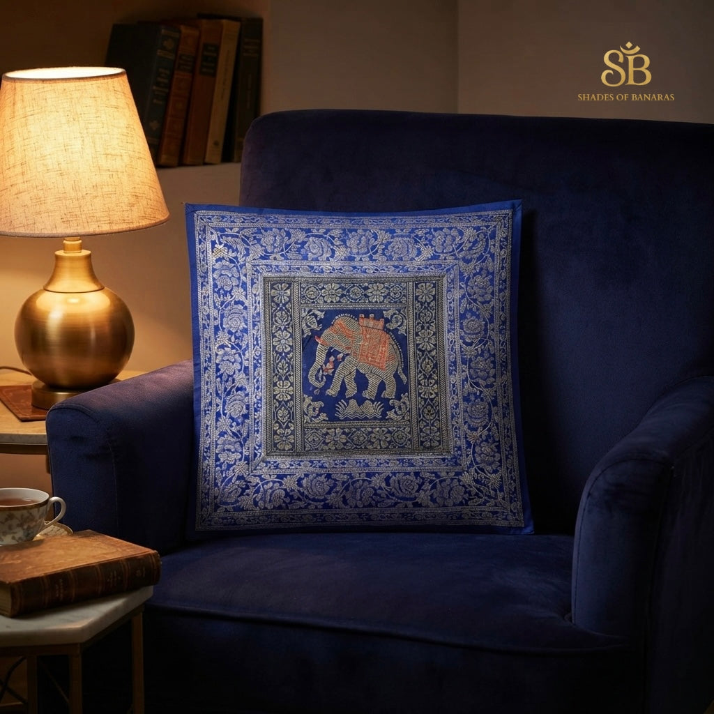 Blue brocade Banarasi cushion cover with elephant motif on a navy velvet armchair