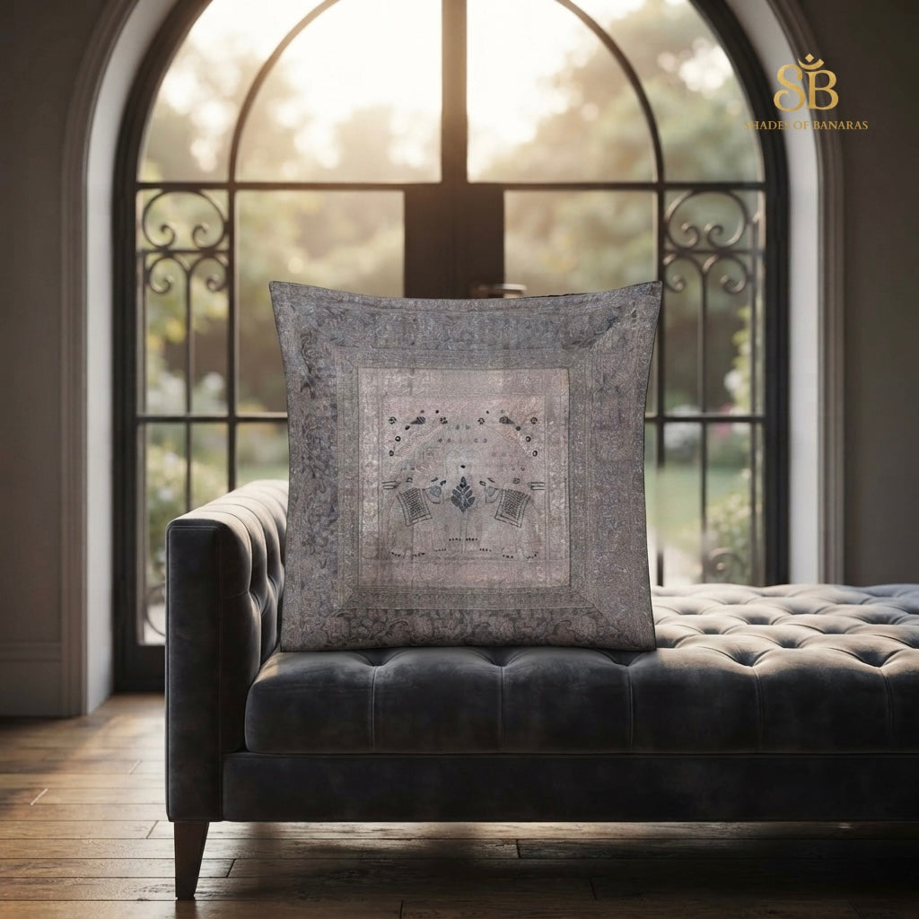 Grey brocade Banarasi cushion cover with fine silver floral panel on a tufted sofa