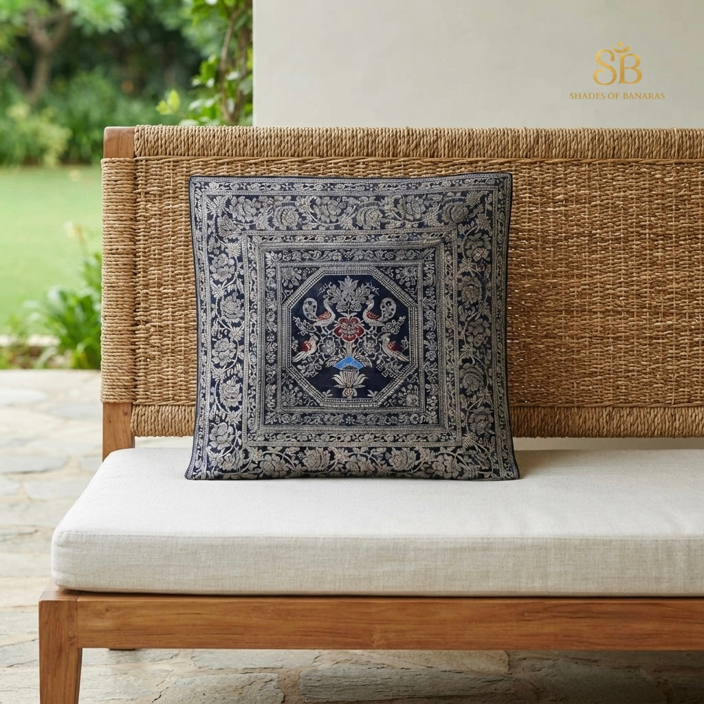 Blue brocade Banarasi cushion cover with silver octagon urn motif on a cane bench