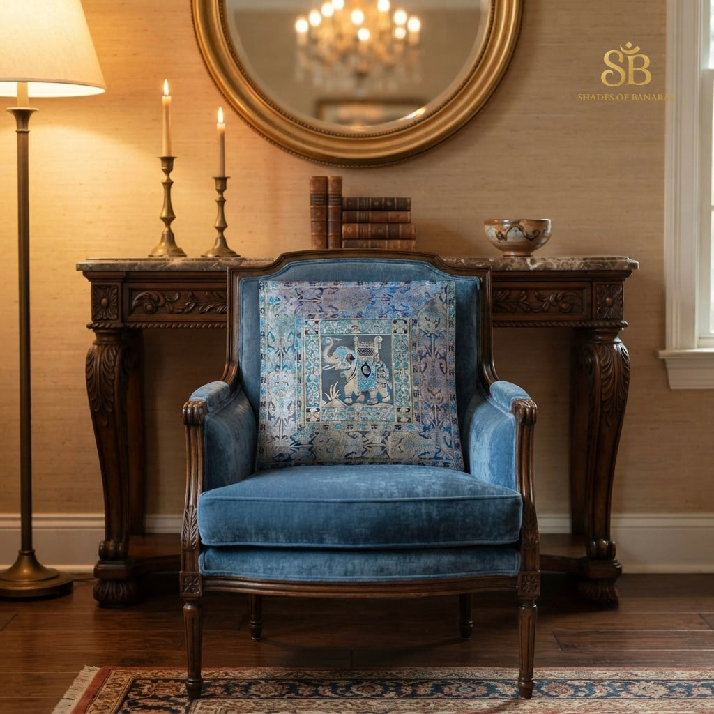 Blue brocade Banarasi cushion cover with elephant motif on a powder-blue velvet chair